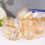 Shop the Golden Pebble Glass Tumbler at Dollar Empire, featuring a stylish golden-amber color and unique textured finish for everyday drinks.